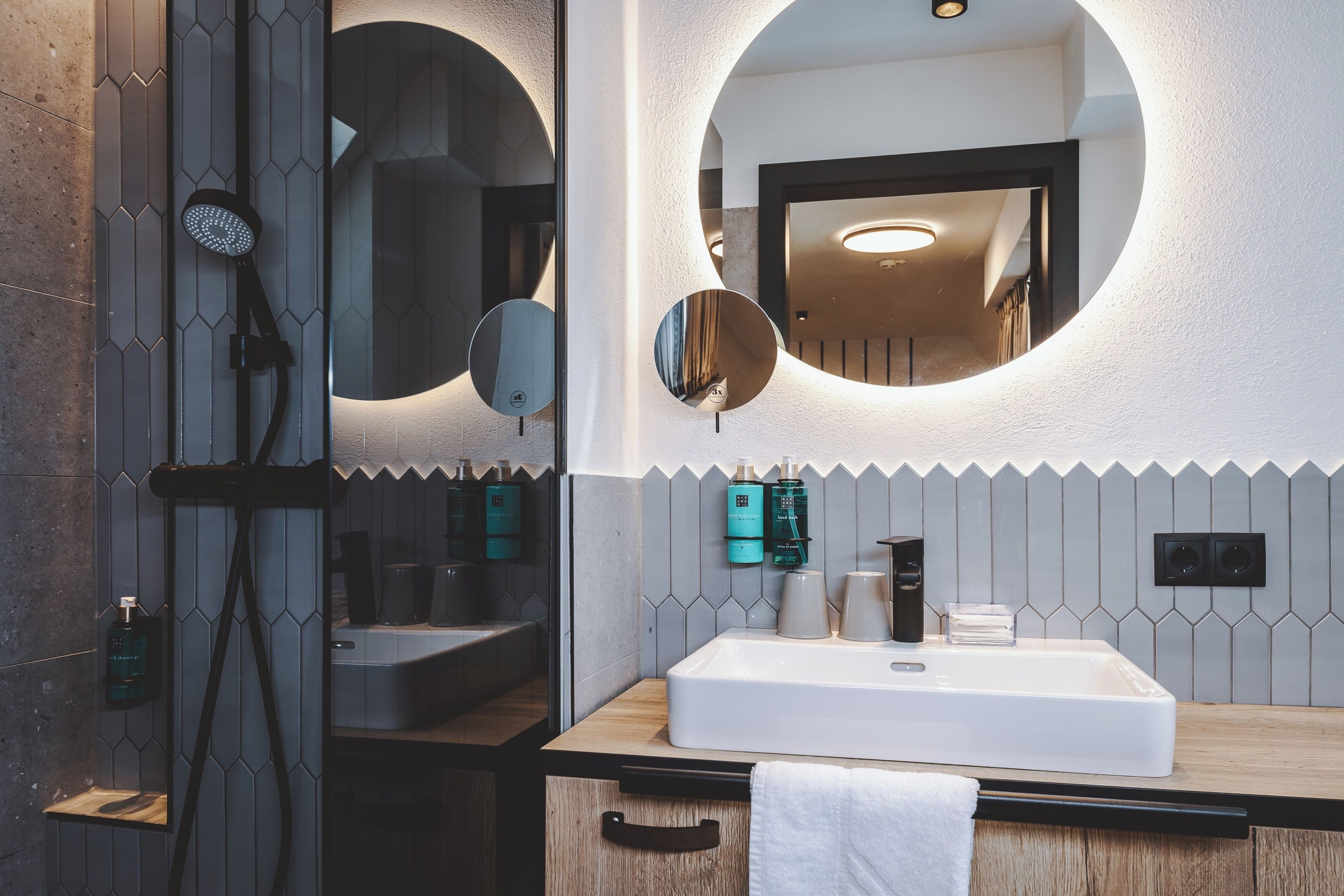 A modern bathroom with a large mirror, a shower, and a sink.
