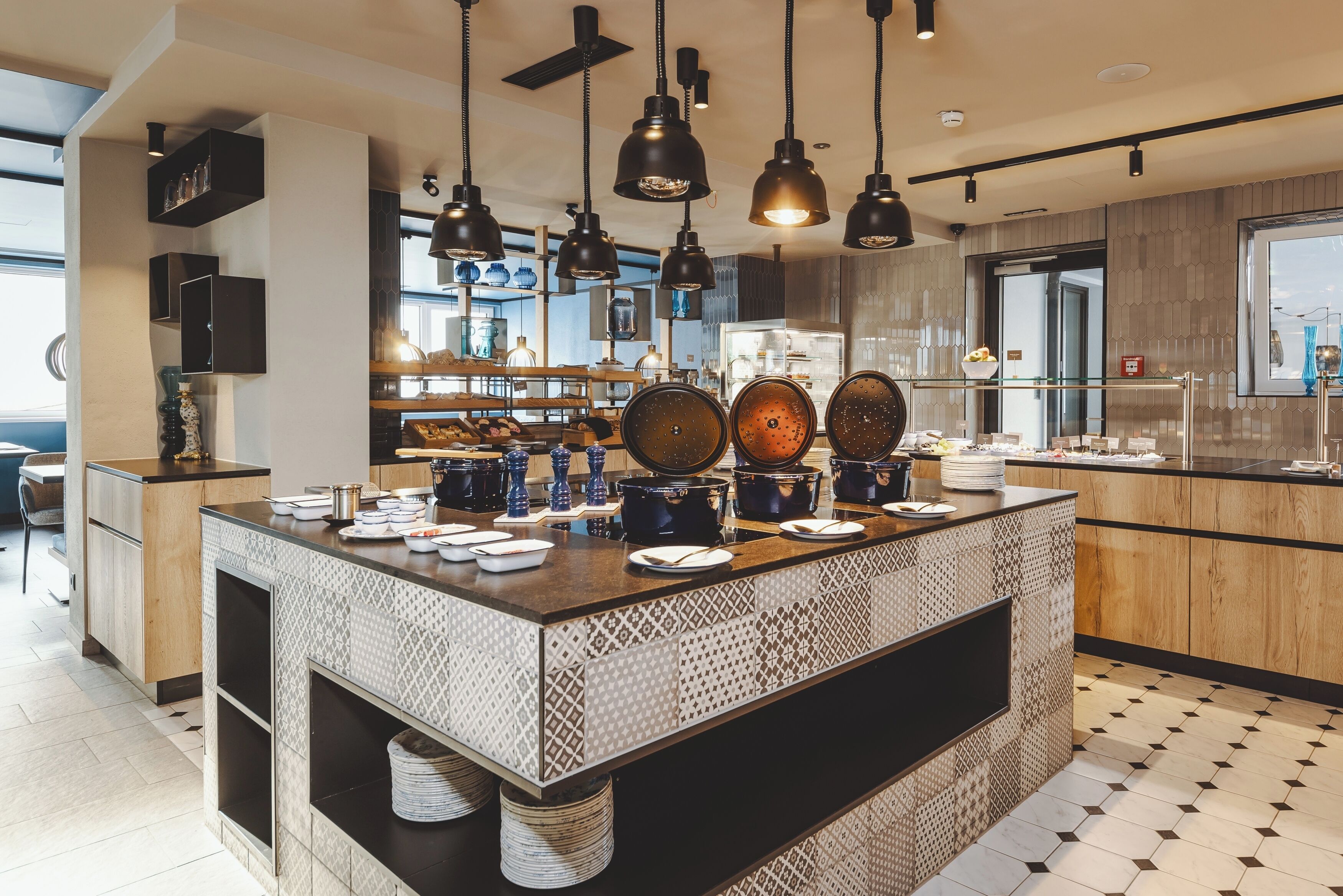 Una cocina moderna con una isla central, iluminación colgante y vistas al área de comedor.