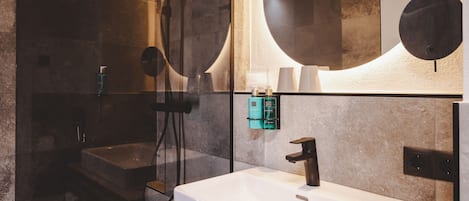 Un baño moderno con un espejo grande, un lavamanos y una ducha.
