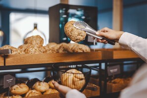 A person selecting a bread roll from a bakery display. - The Gast House Zell am See (Zell am See)