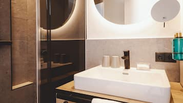 A modern bathroom with a large white sink, a mirror, and a glass shower enclosure.