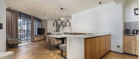 Une cuisine moderne dotée d’un îlot en marbre, de meubles en bois et d’un coin repas avec des chaises et une table.