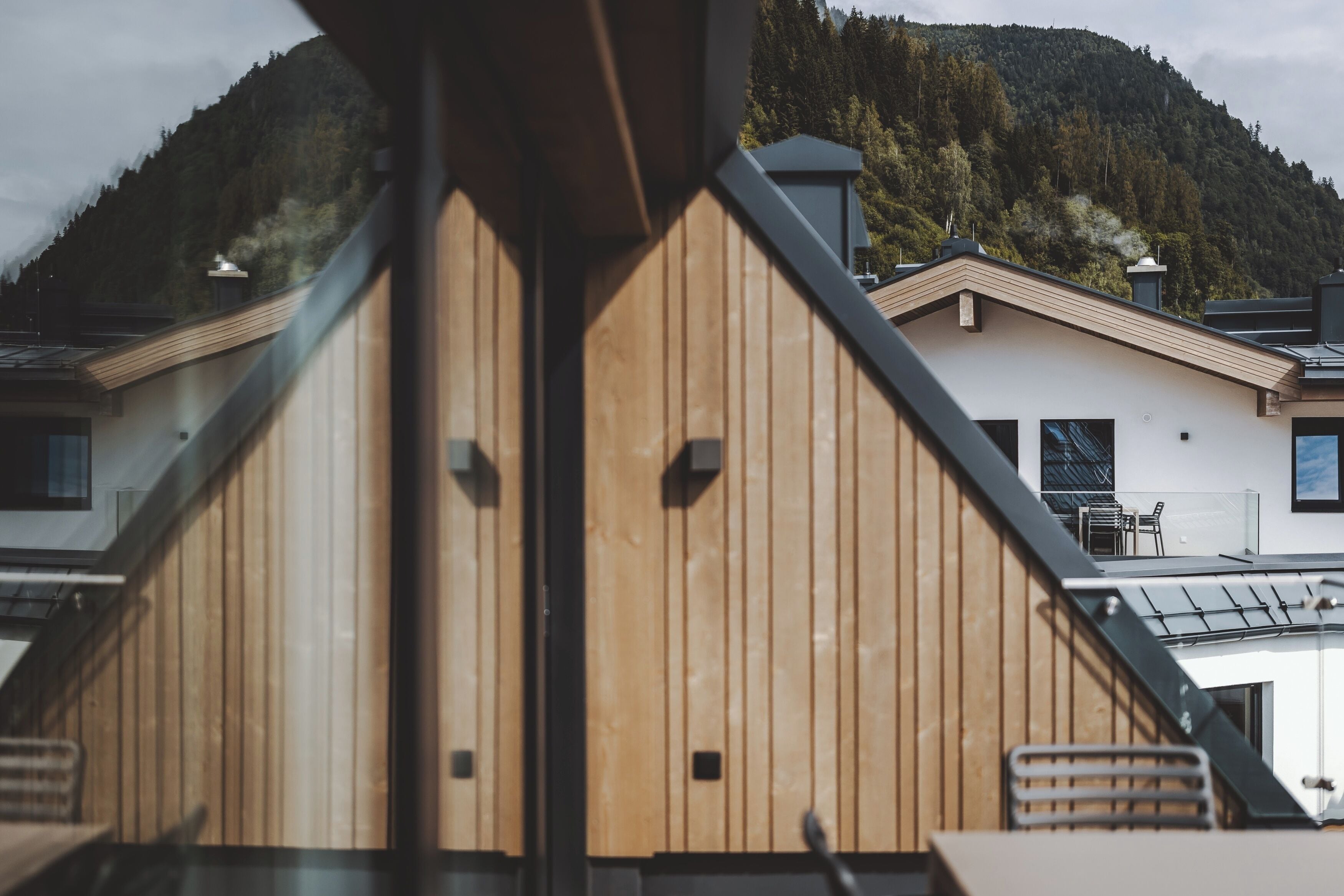 Un bâtiment moderne avec un revêtement en bois et un toit en pente, offrant une vue sur une montagne boisée.