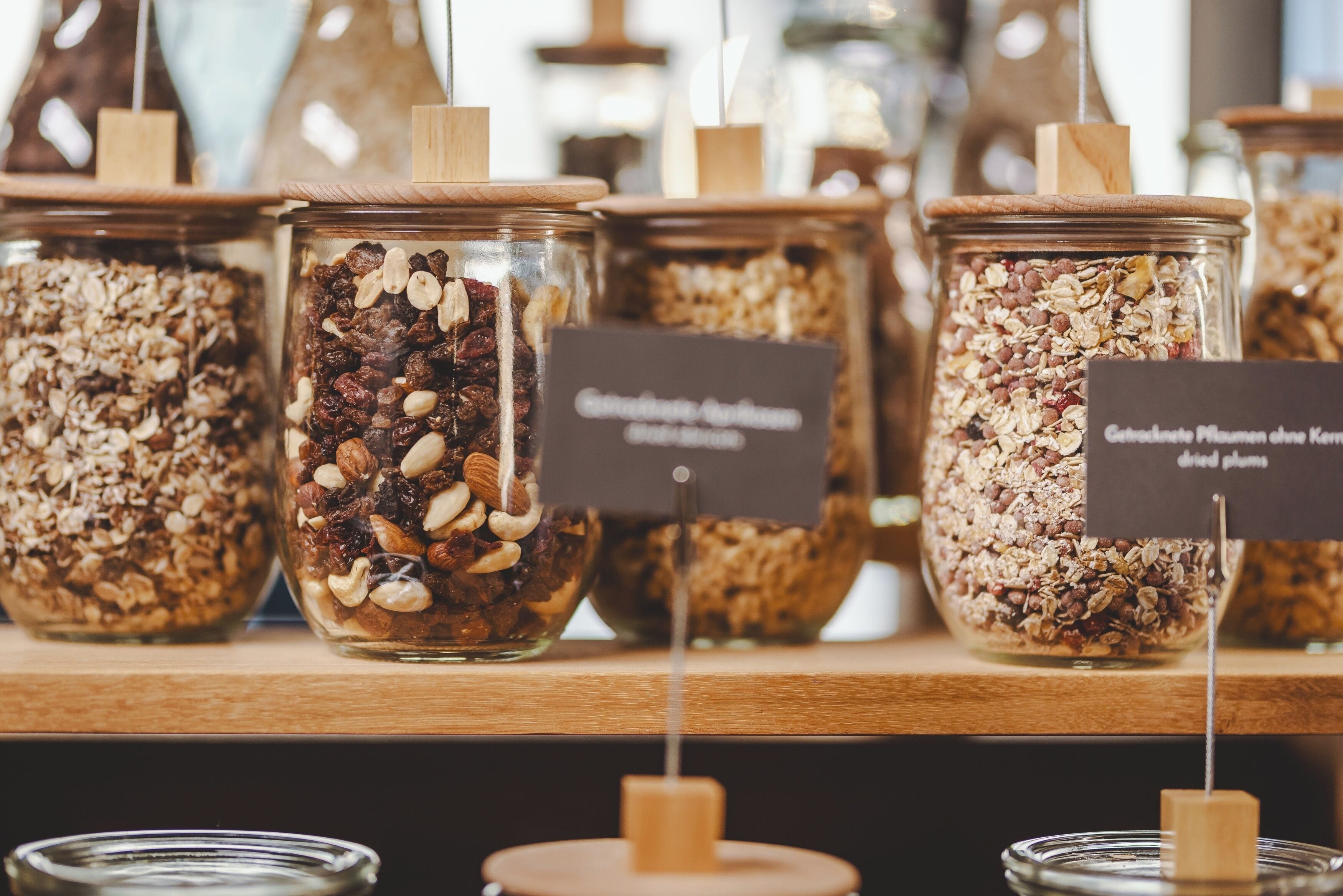 A display of various granola and cereal bars in glass jars with wooden lids and labels.
