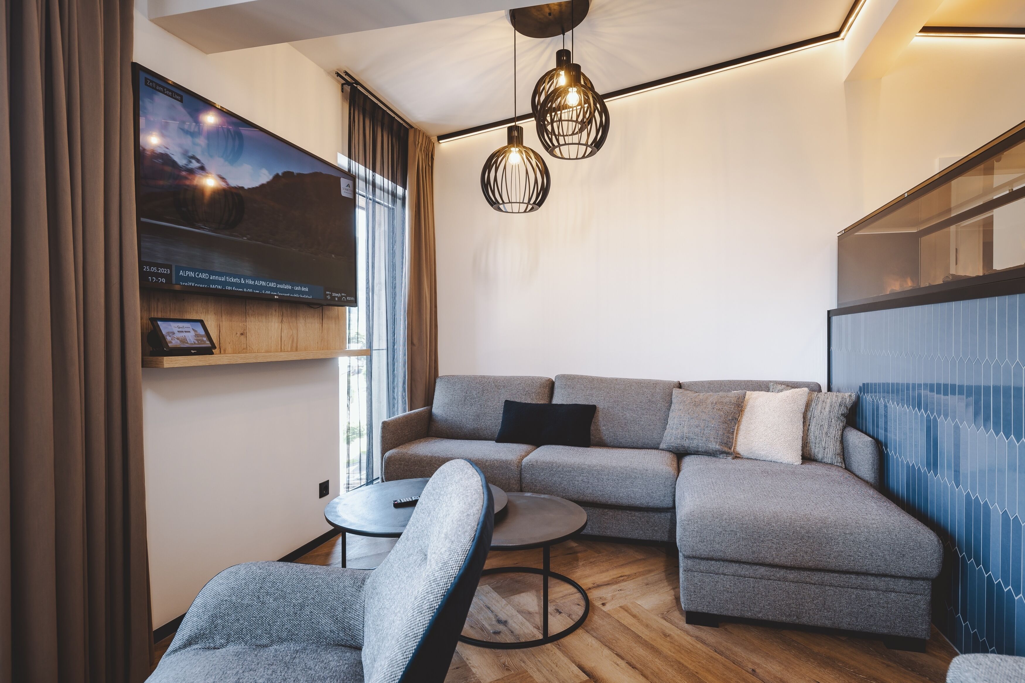 A modern living room with a sectional sofa, a round coffee table, and a TV mounted on the wall.