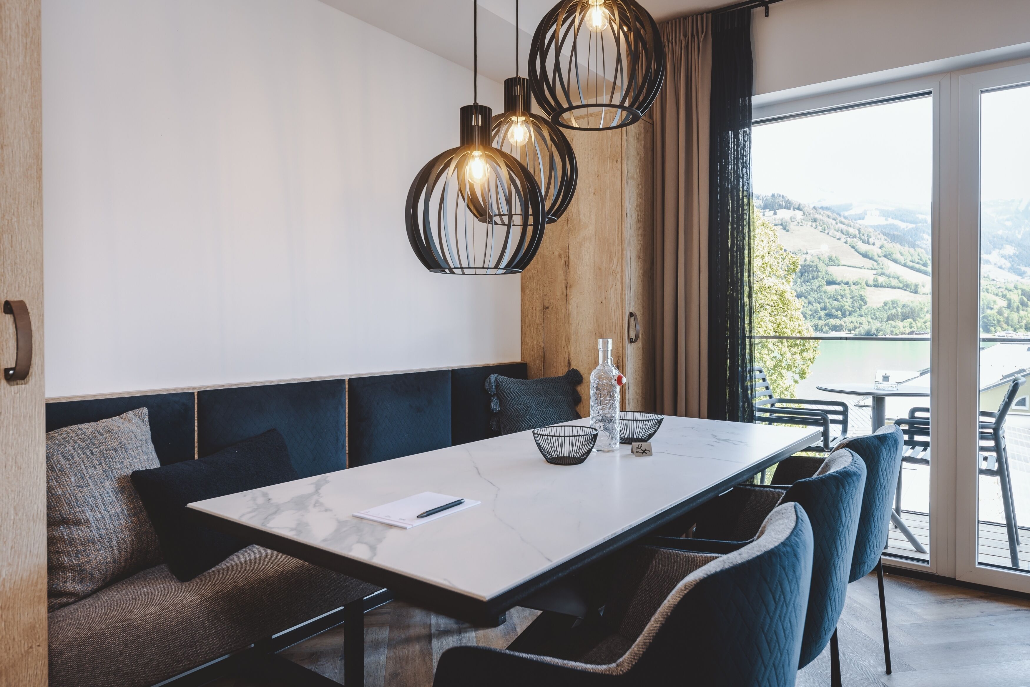A modern dining area with a marble table, black chairs, and pendant lighting.