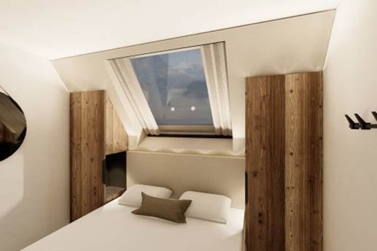 Une chambre avec un puits de lumière, un lit, un miroir rond et des panneaux en bois.