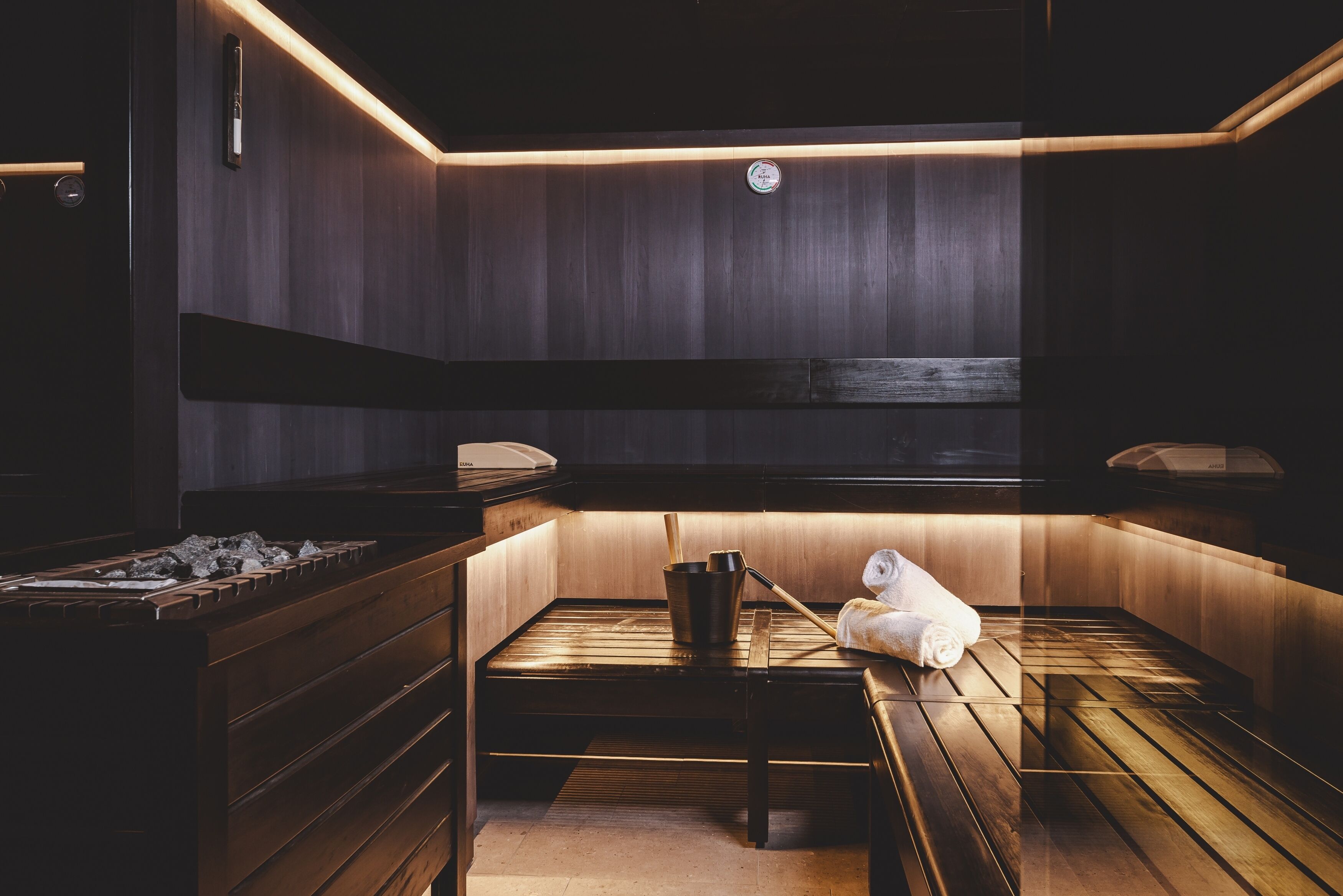 A sauna with wooden benches, a towel, and a bucket.