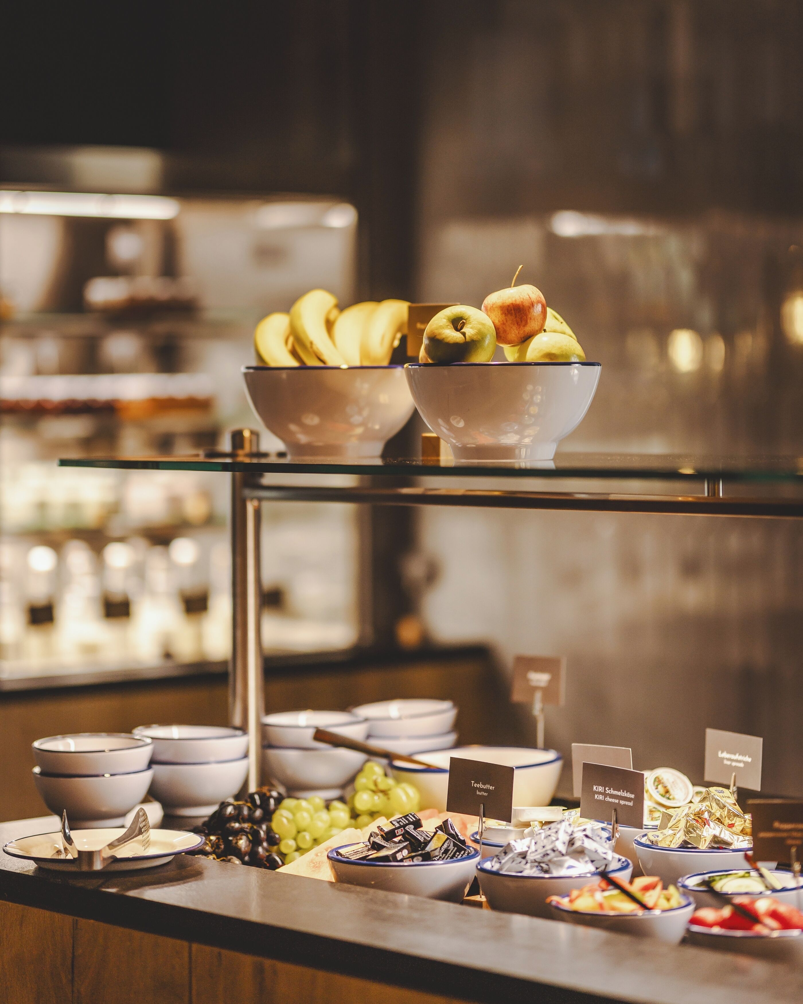 A buffet with various food items including bananas, apples, and grapes.