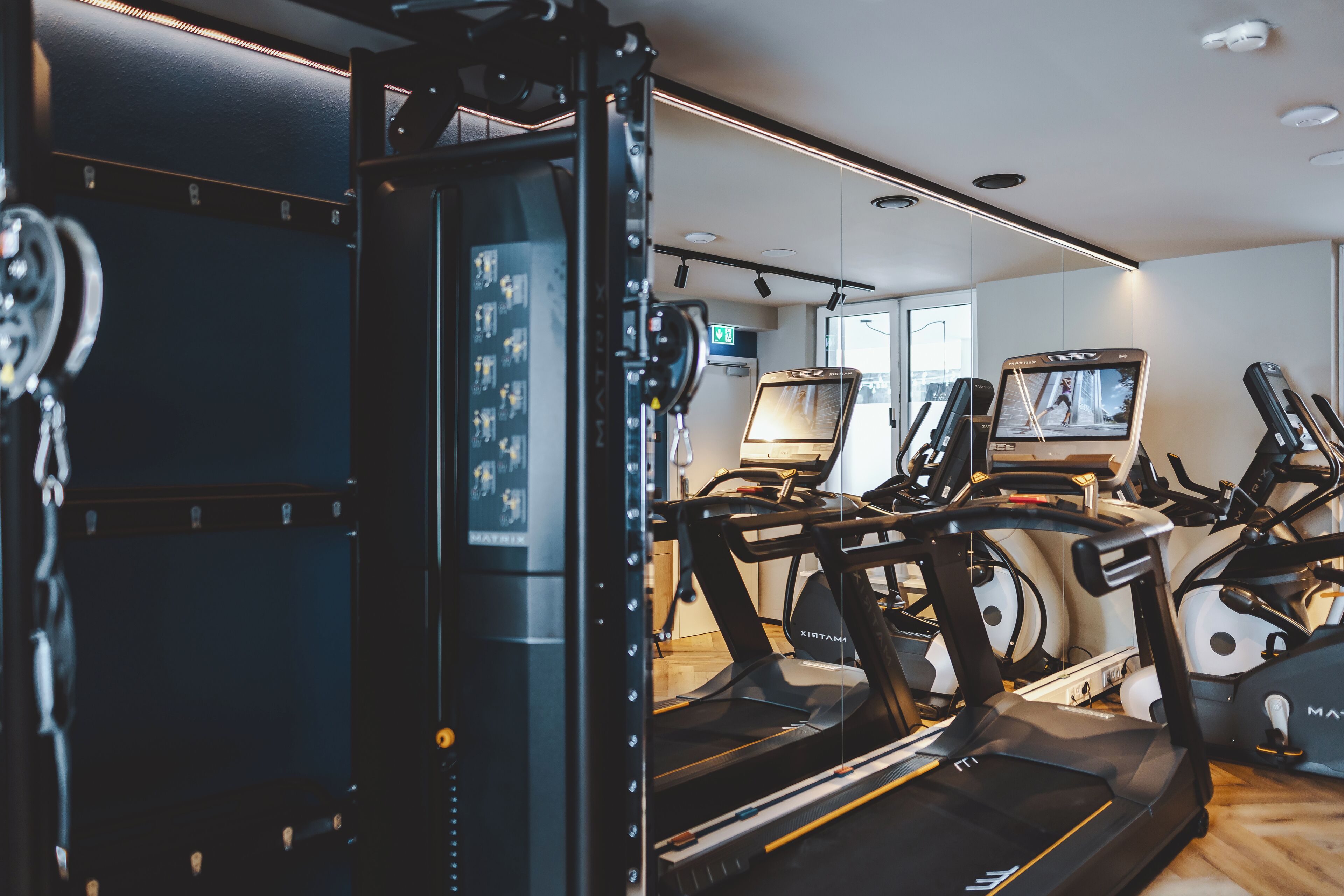 A gym with treadmills, a weight machine, and a television screen.
