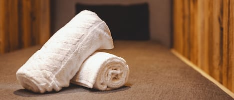 Una habitación de madera con una cama, un almohadón y una toalla enrollada.