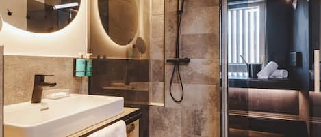A modern bathroom with a large mirror, a sink, and a shower area.
