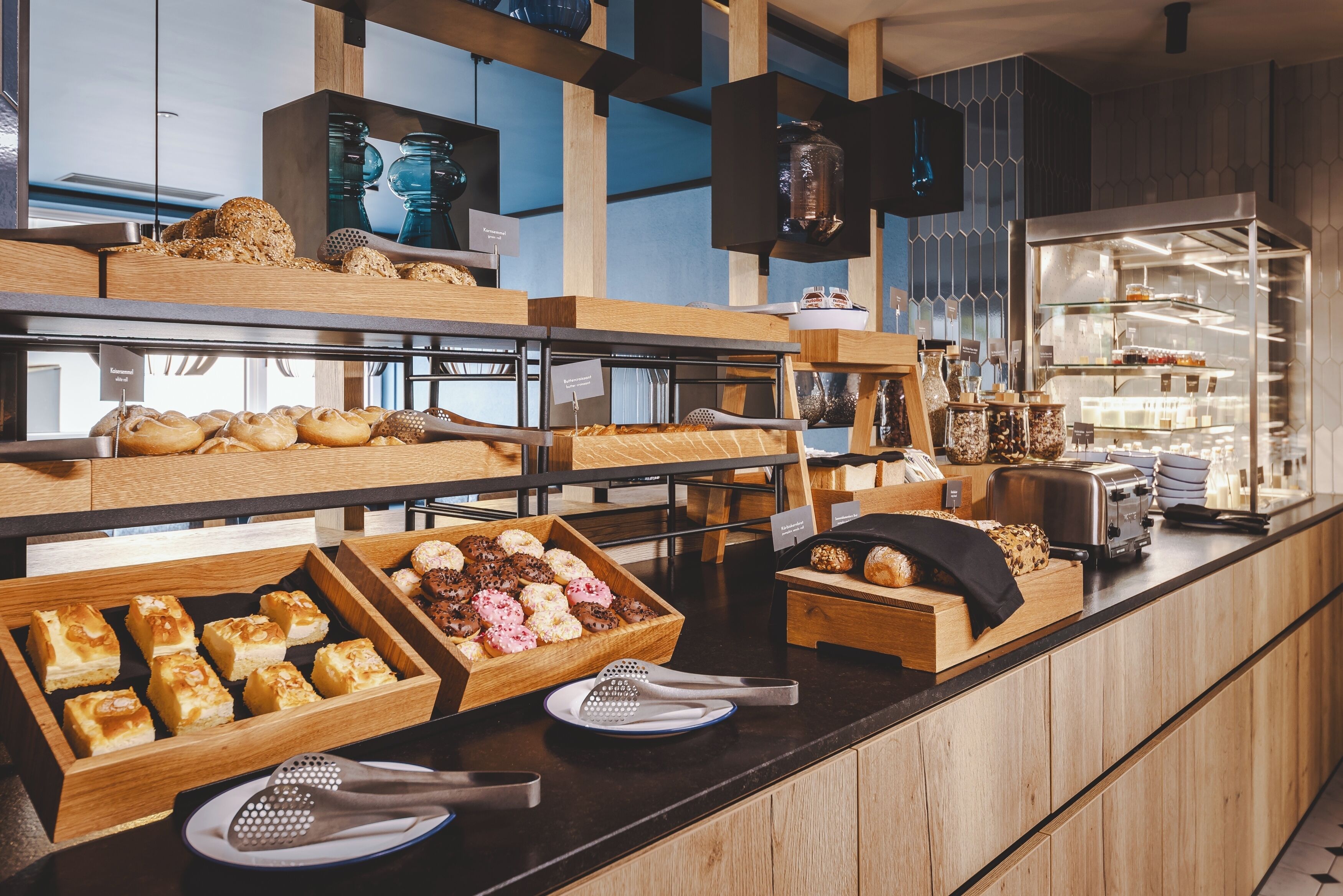 Een buffet met verschillende gebakjes en patisserie, waaronder taarten en koekjes, gepresenteerd op houten etagères en schalen.