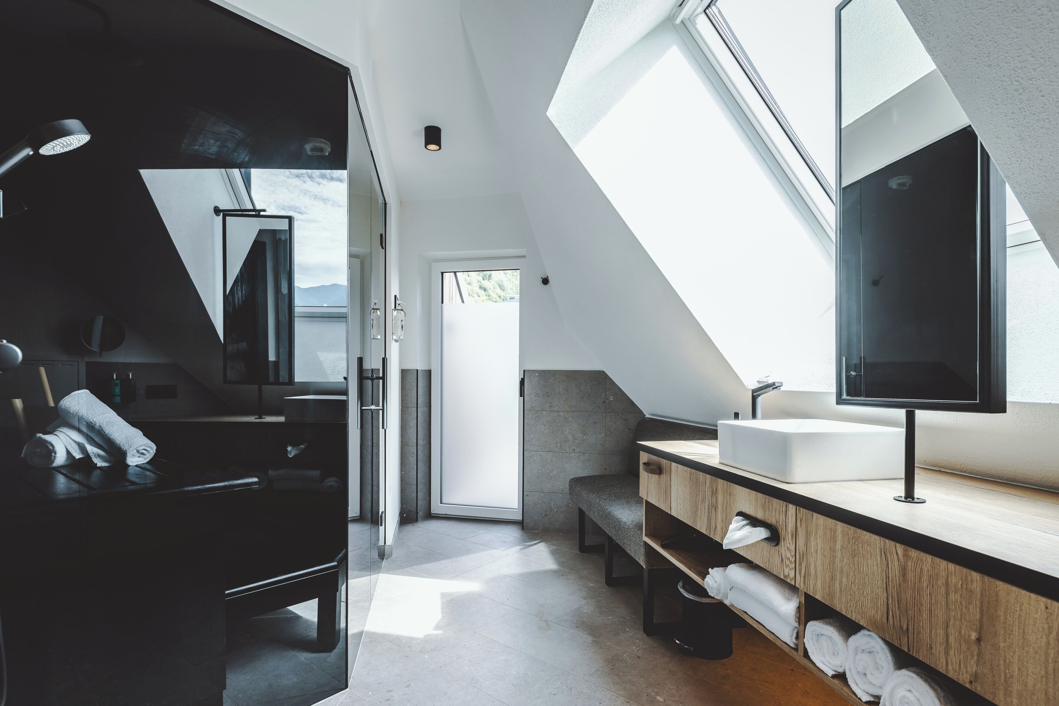 Ein modernes Badezimmer mit Oberlicht, einem großen Spiegel und einem Holzlagerfläschchen.