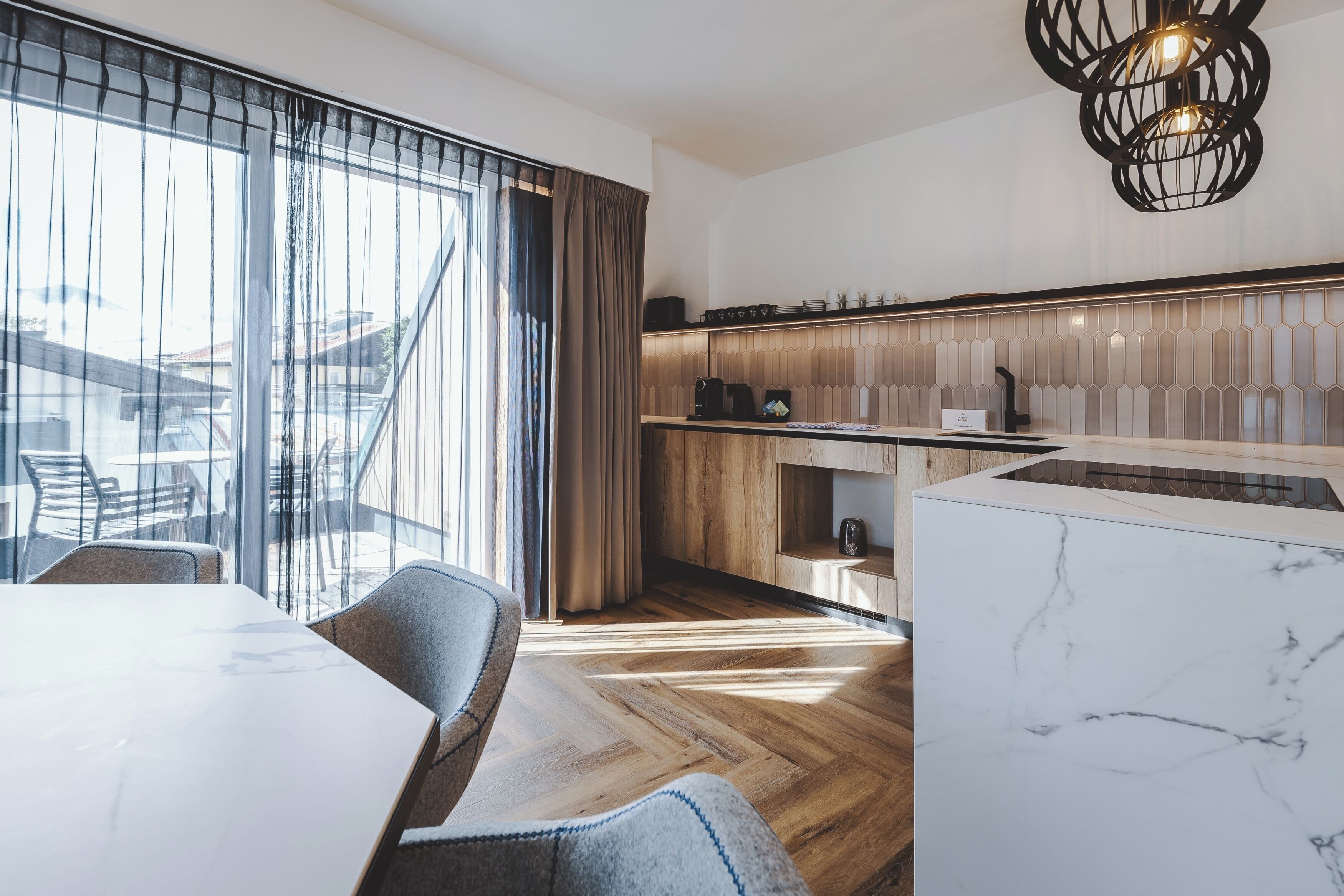 Een moderne keuken met een houten aanrecht, een marmeren kookeiland en uitzicht op het buitenterrein.