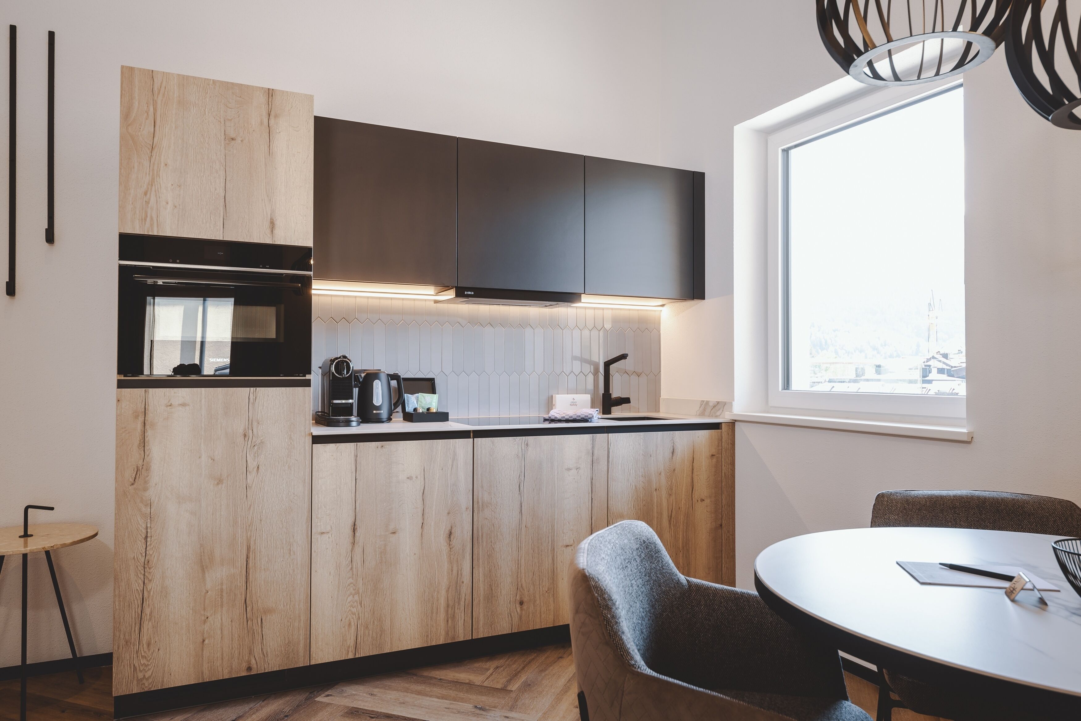 Una cocina moderna con armarios de madera, horno empotrado y ventana con vistas a la ciudad.