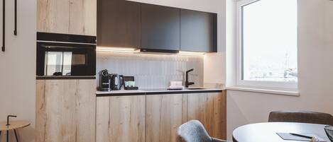A modern kitchen with wooden cabinets, a built-in oven, and a window providing a view of the city.