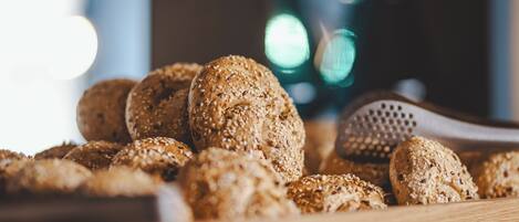 A wooden cutting board with several round, sesame-seed-topped bread rolls.