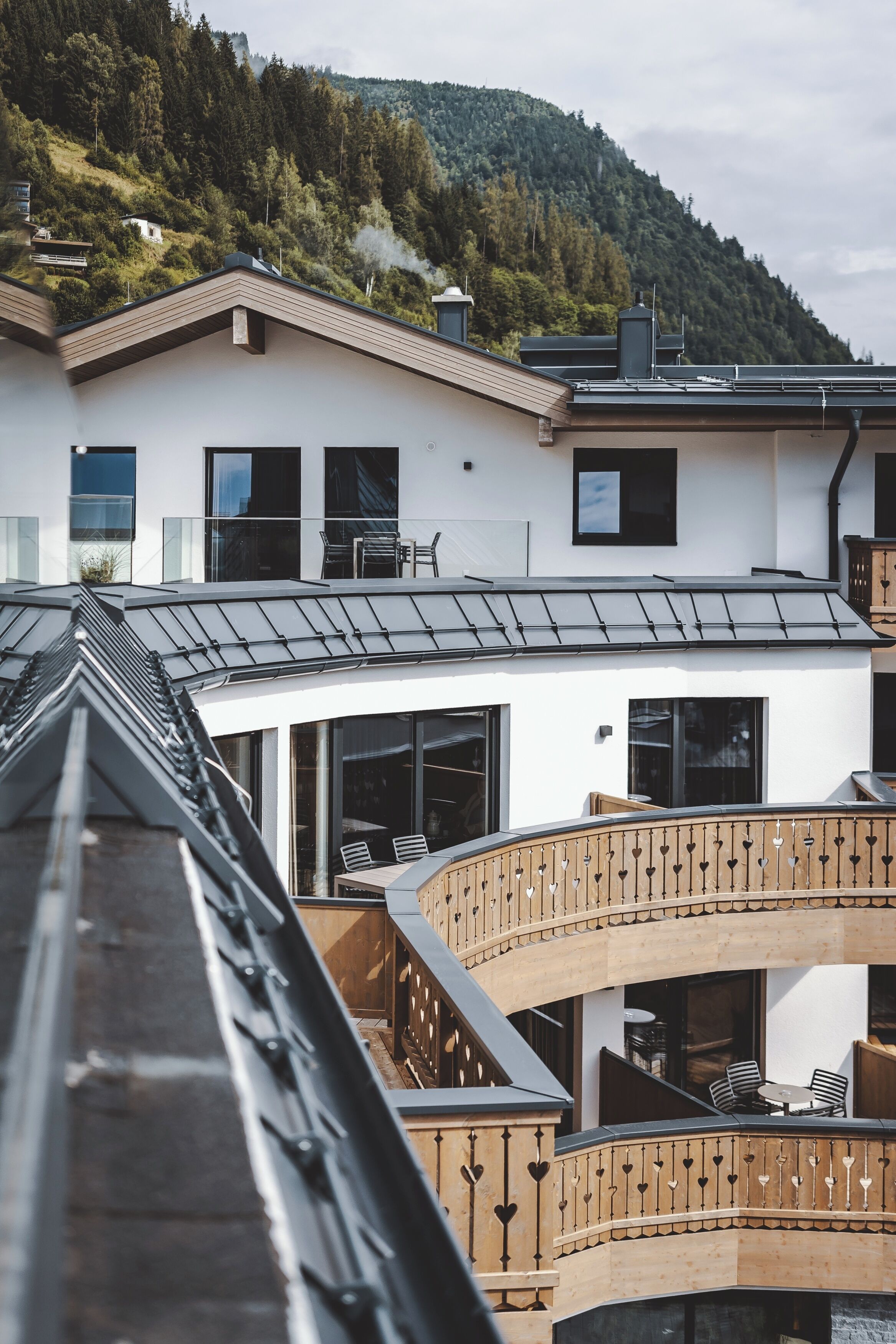 A modern building with a sloped roof, large windows, and a balcony with heart-shaped railings.