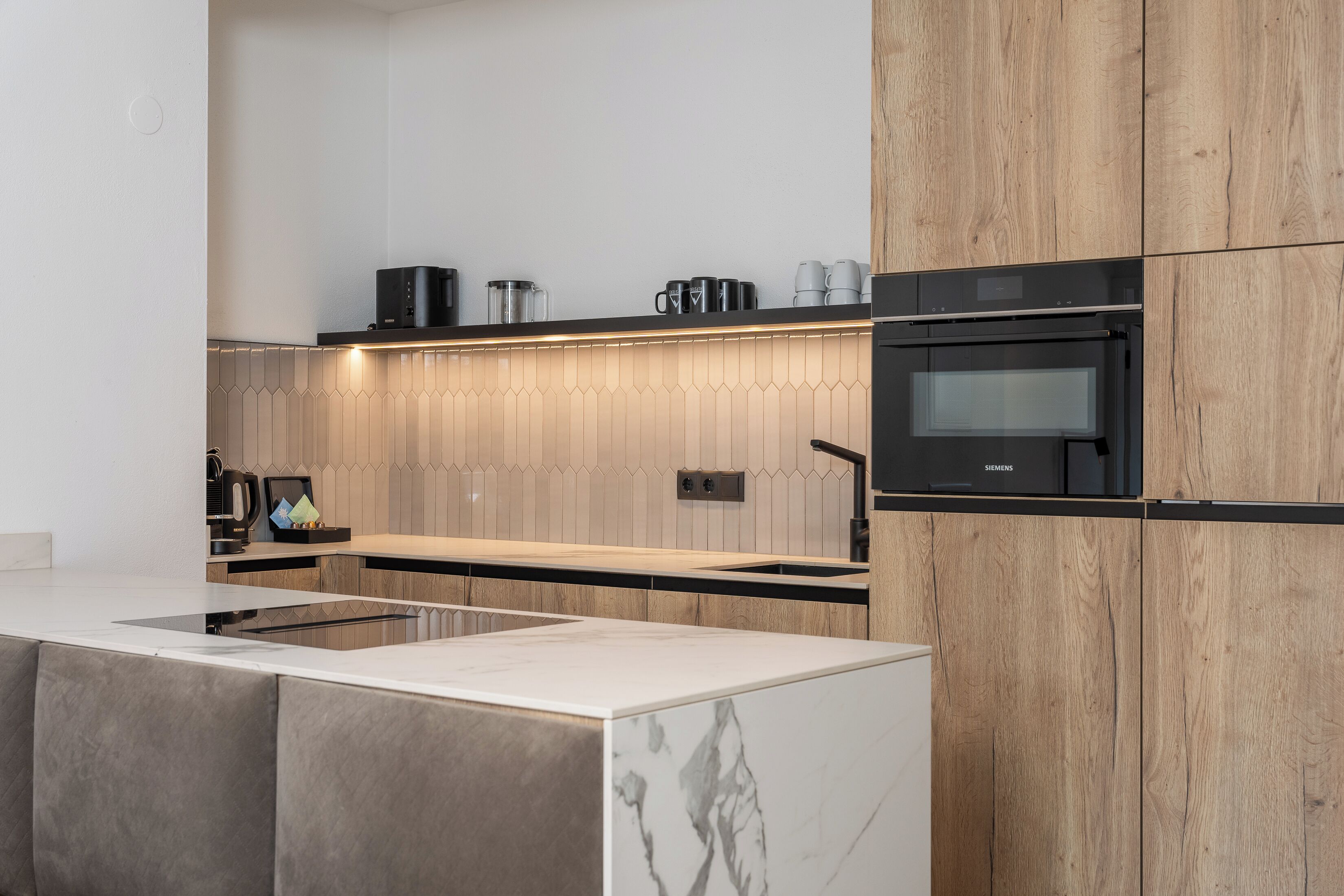 Una cocina moderna con encimera de mármol, armarios de madera y horno empotrado.