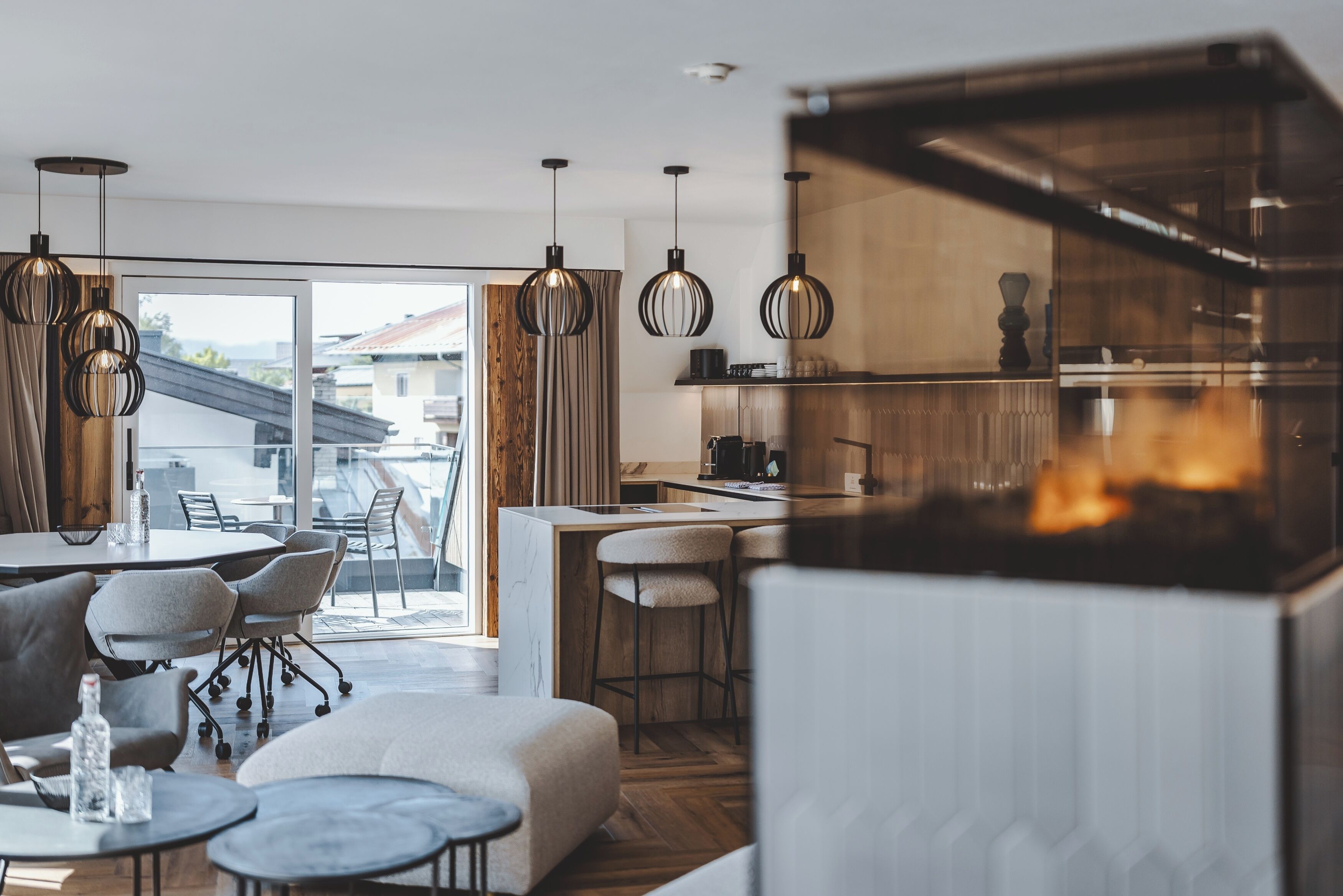 Une cuisine moderne dotée d’un îlot central, de luminaires suspendus et offrant une vue sur l’extérieur.