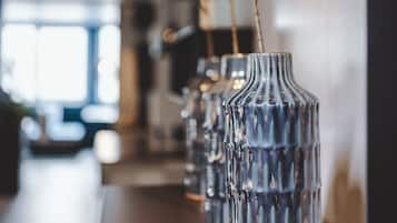 A row of clear glass vases with dried branches on a wooden table in a well-lit indoor space.