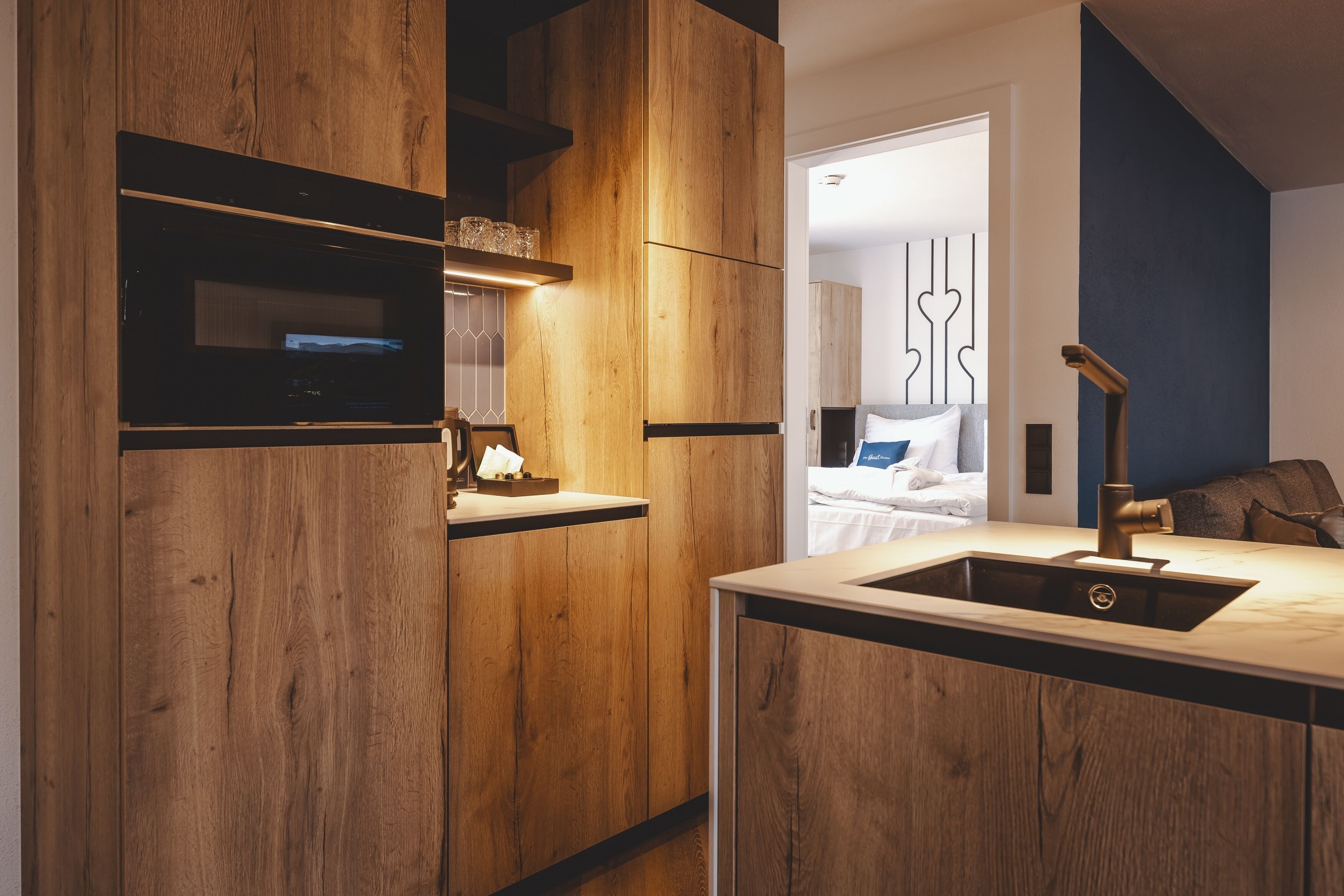 A modern kitchen with wooden cabinetry, a built-in oven, and a sink with a faucet.