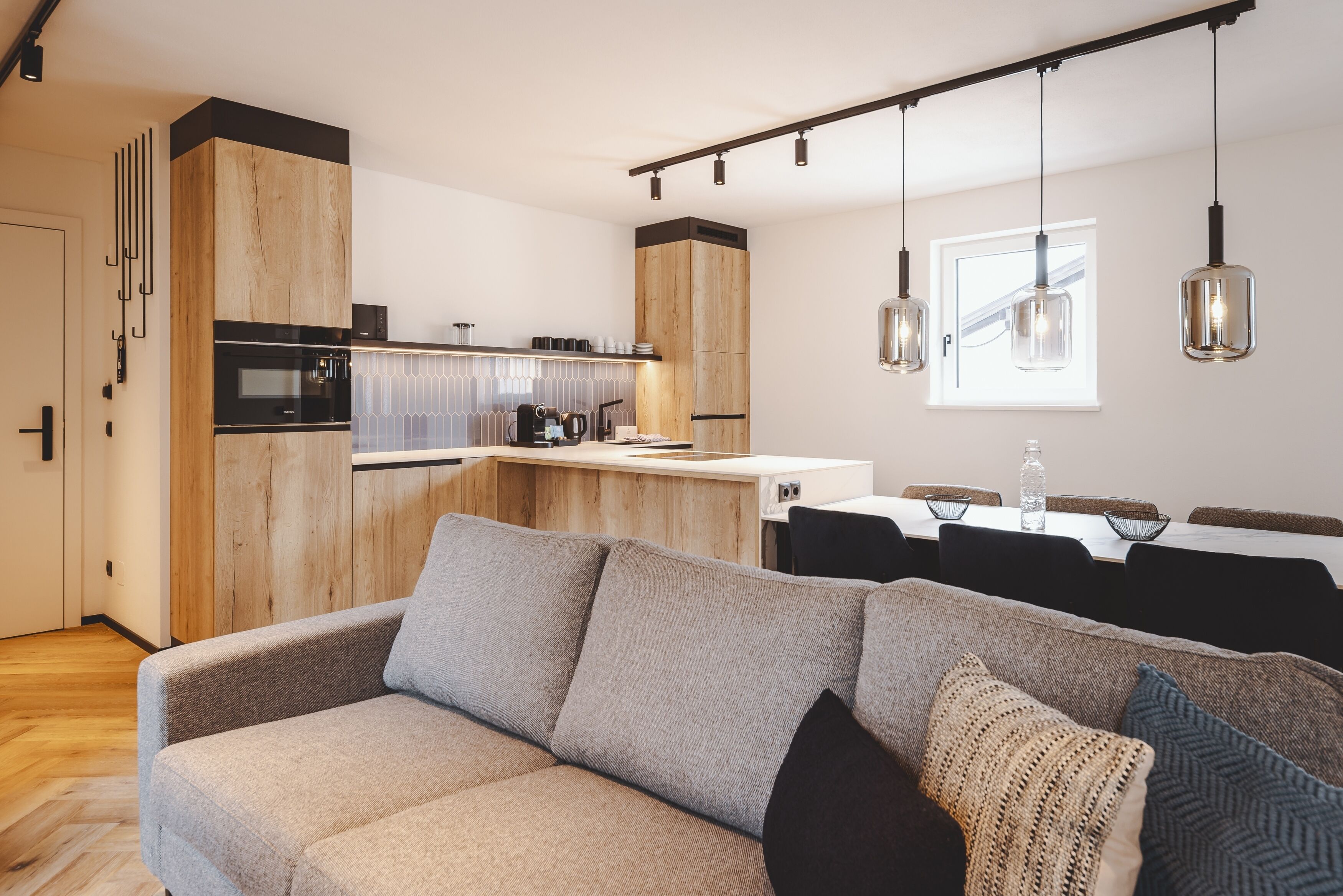 Eine moderne Küche mit Holzschränken, einem eingebauten Ofen und einem Essbereich mit Tisch und Stühlen.