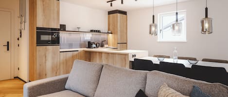 A modern kitchen with wooden cabinets, a built-in oven, and a dining area with a table and chairs.