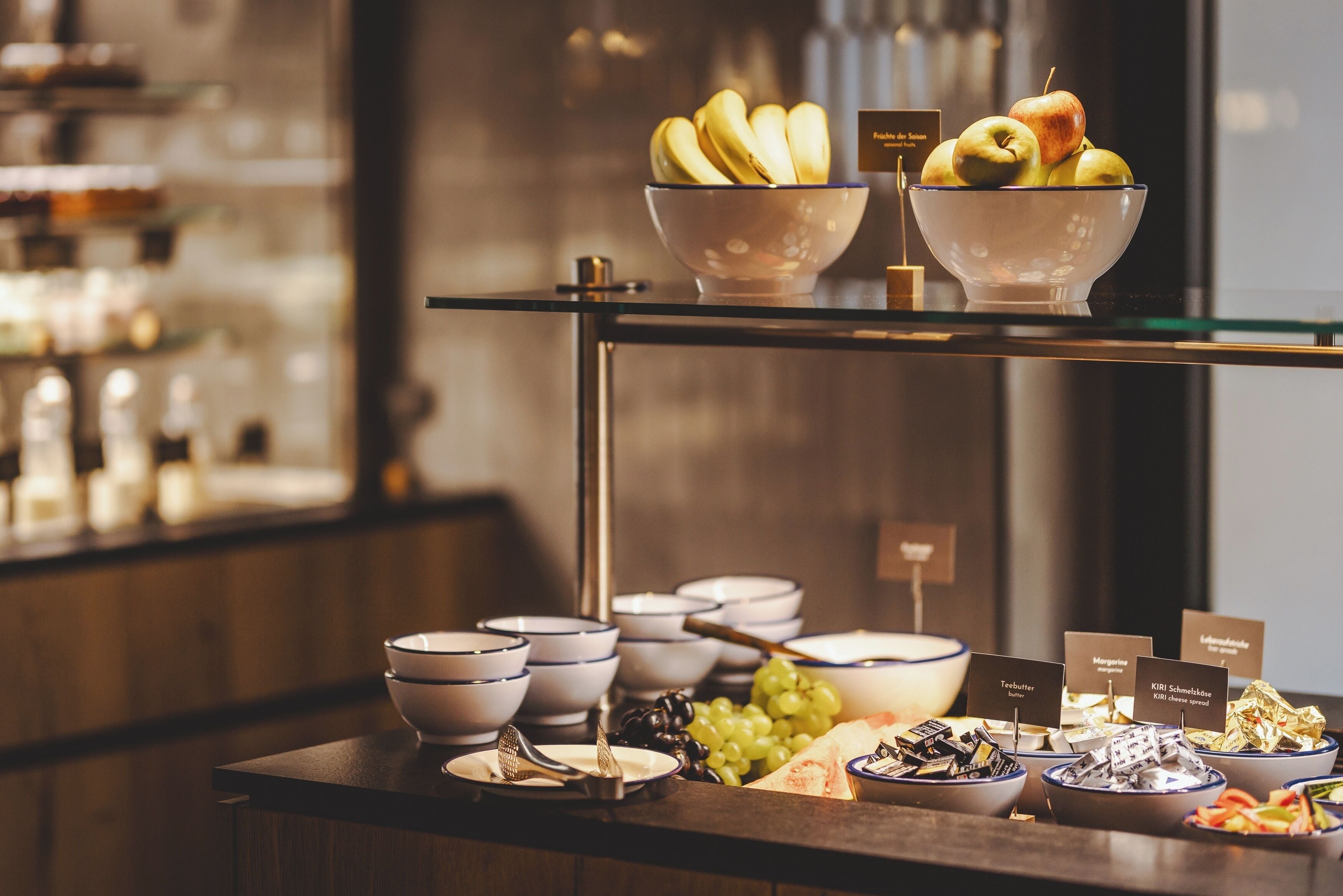 Una barra de buffet con diversos alimentos y recipientes etiquetados.