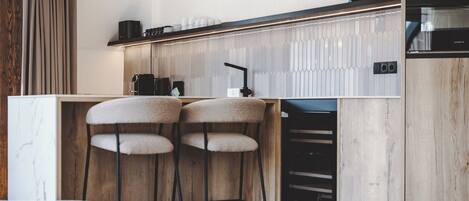 A modern kitchen with pendant lights, bar stools, and a built-in oven.