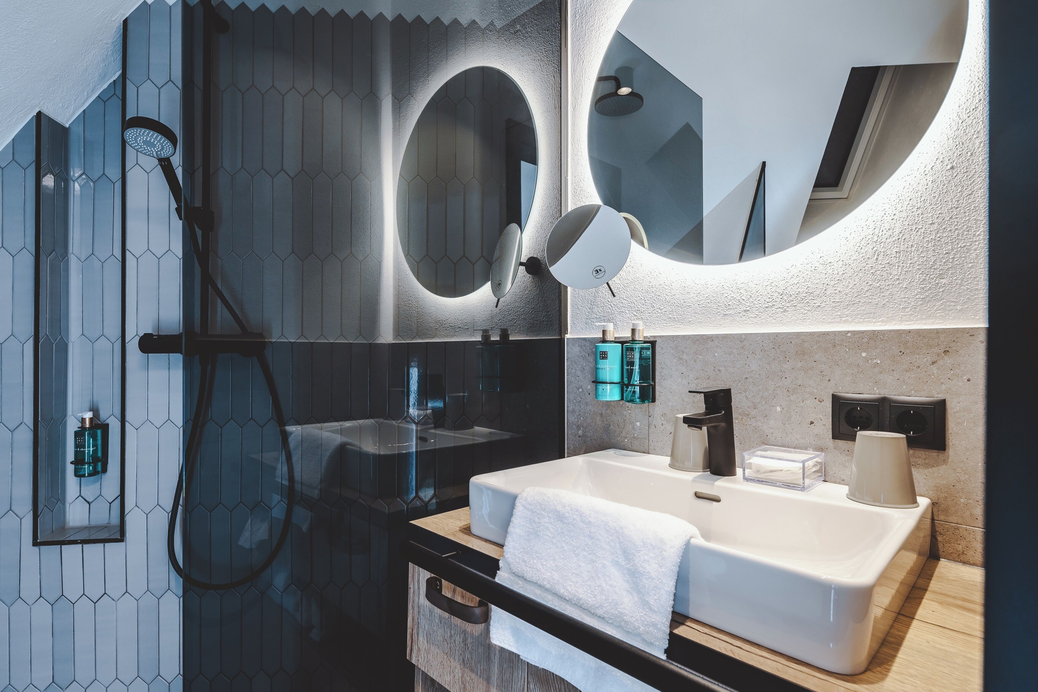 A modern bathroom with a large mirror, a bathtub, and a sink.
