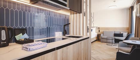 Una cocina moderna con encimera de madera, horno empotrado y microondas. Hay una zona de estar con sofá y sillones.