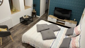 A modern bedroom with a bed, a TV, a small table, and a chair.