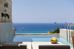 A poolside view with a bowl of bananas, lounge chairs, and a clear view of the ocean. - Falasarna Luxury Villas - Holiways Collection (Kissamos)
