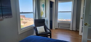 Ein Schlafzimmer mit Meerblick, einem schwarzen Sessel und einem Bett.