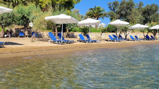 A beach with clear water, blue lounge chairs, and white umbrellas. - O Paradise Beach Resort & Spa (Eretria)
