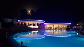 A nighttime pool area with two illuminated structures, one with a bar and the other with seating. - O Paradise Beach Resort & Spa (Eretria)