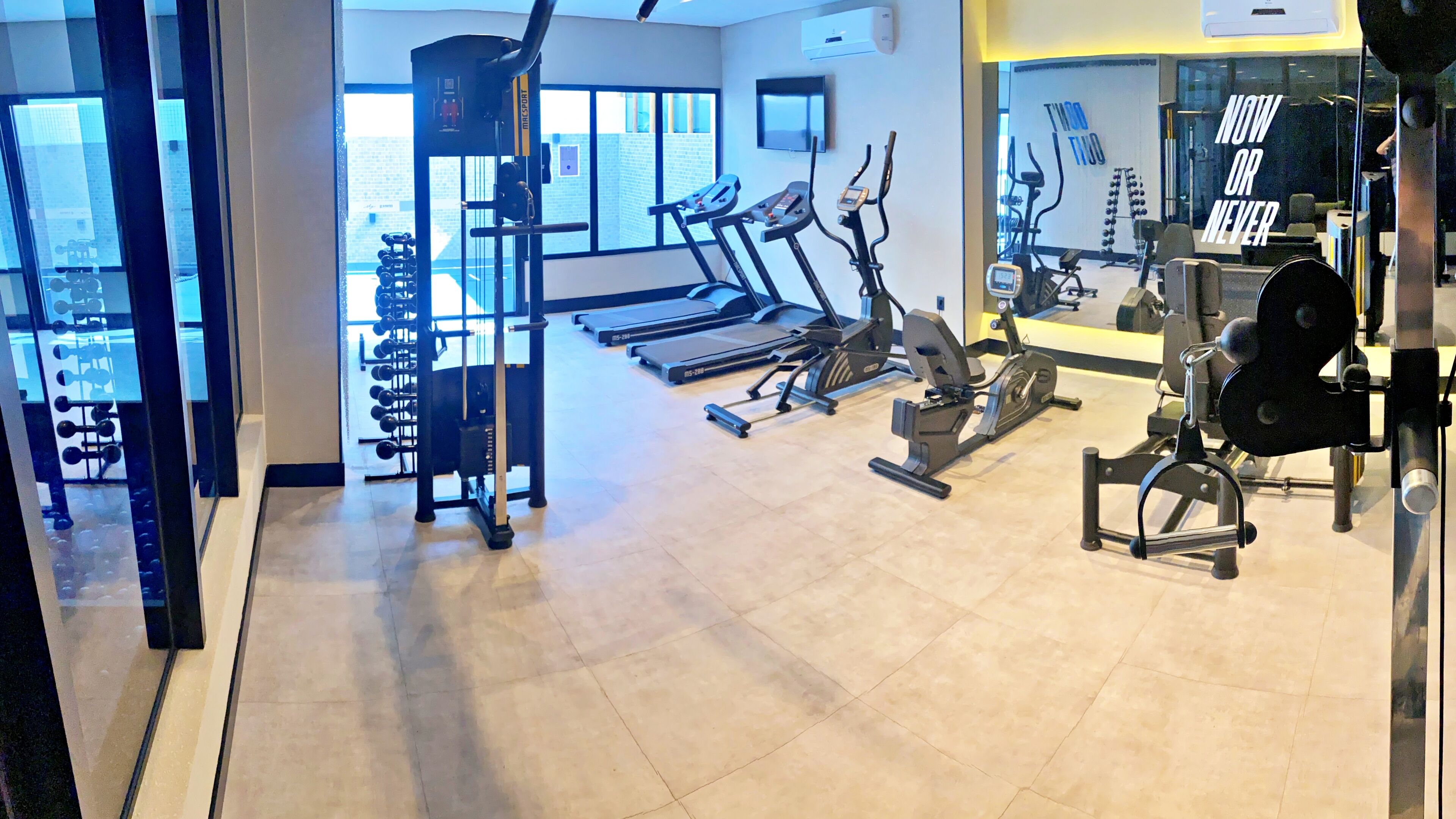 A gym with treadmills, elliptical machines, and weightlifting equipment.