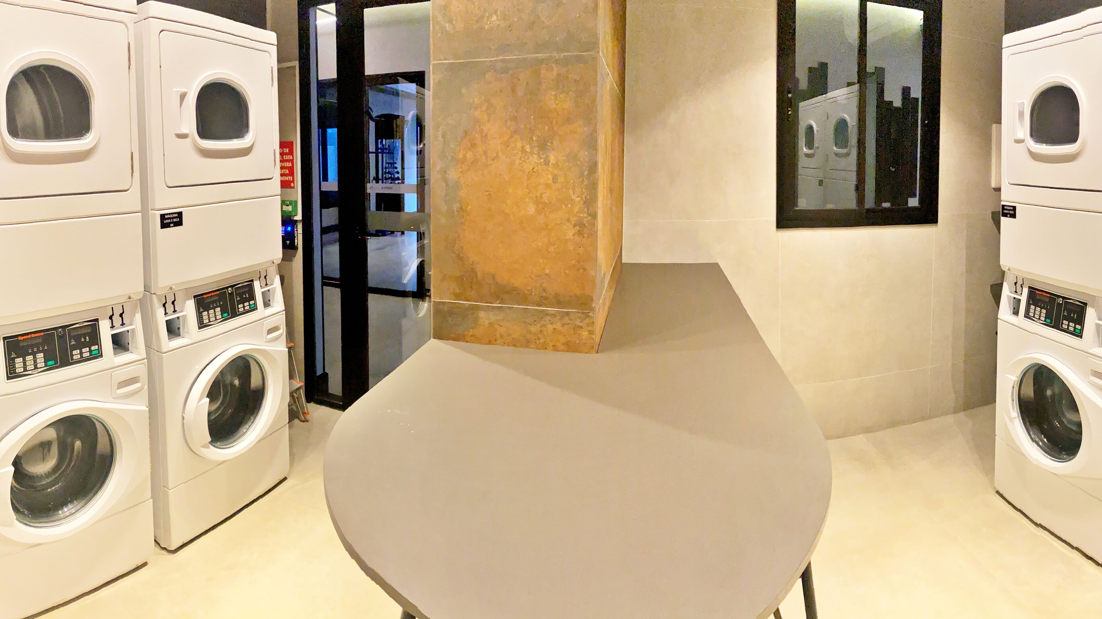 A laundry room with multiple stacked washing machines and a large, empty table in the center.