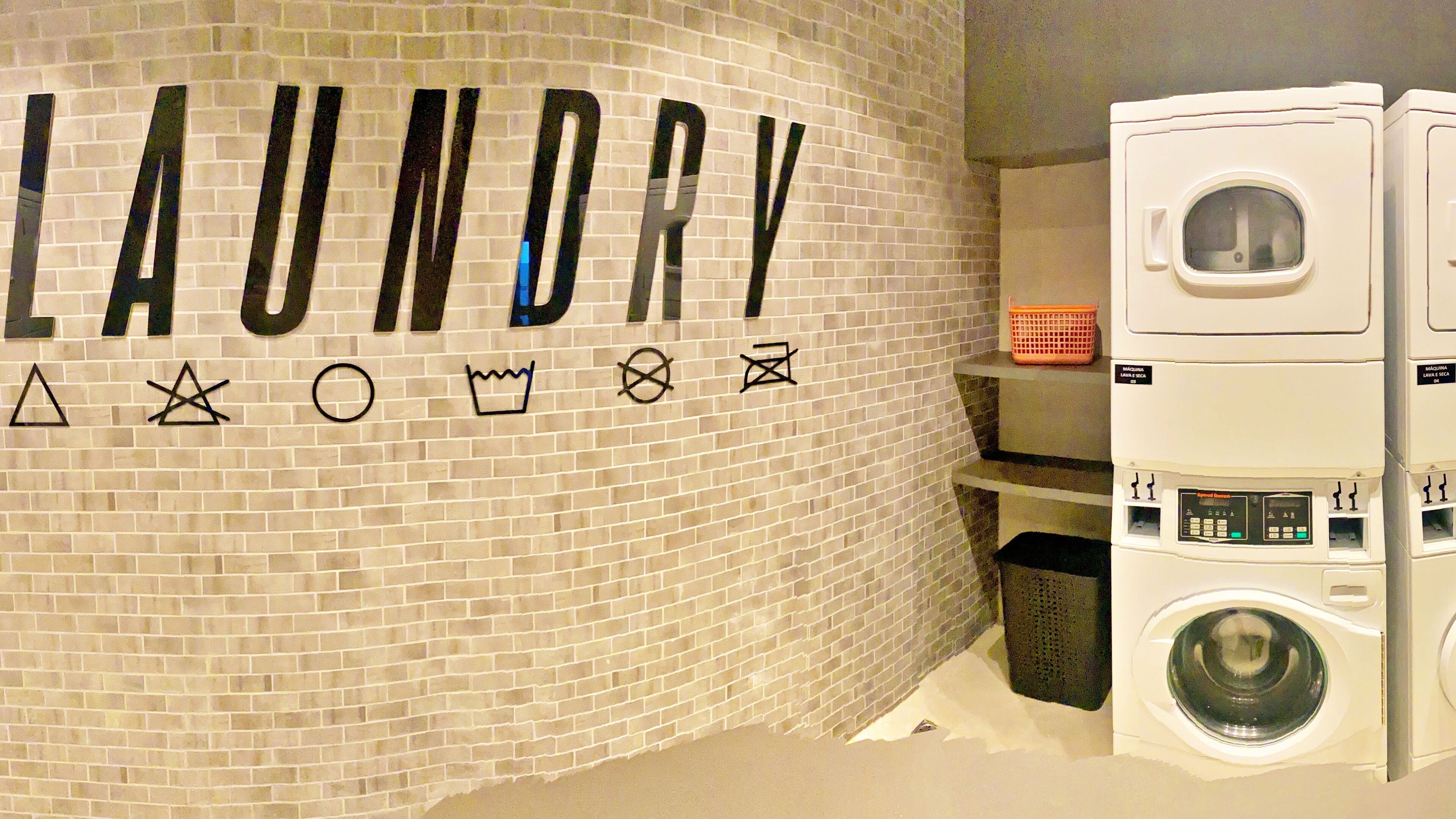 A laundry area with a brick wall and a large sign spelling "LAUNDRY" with symbols.