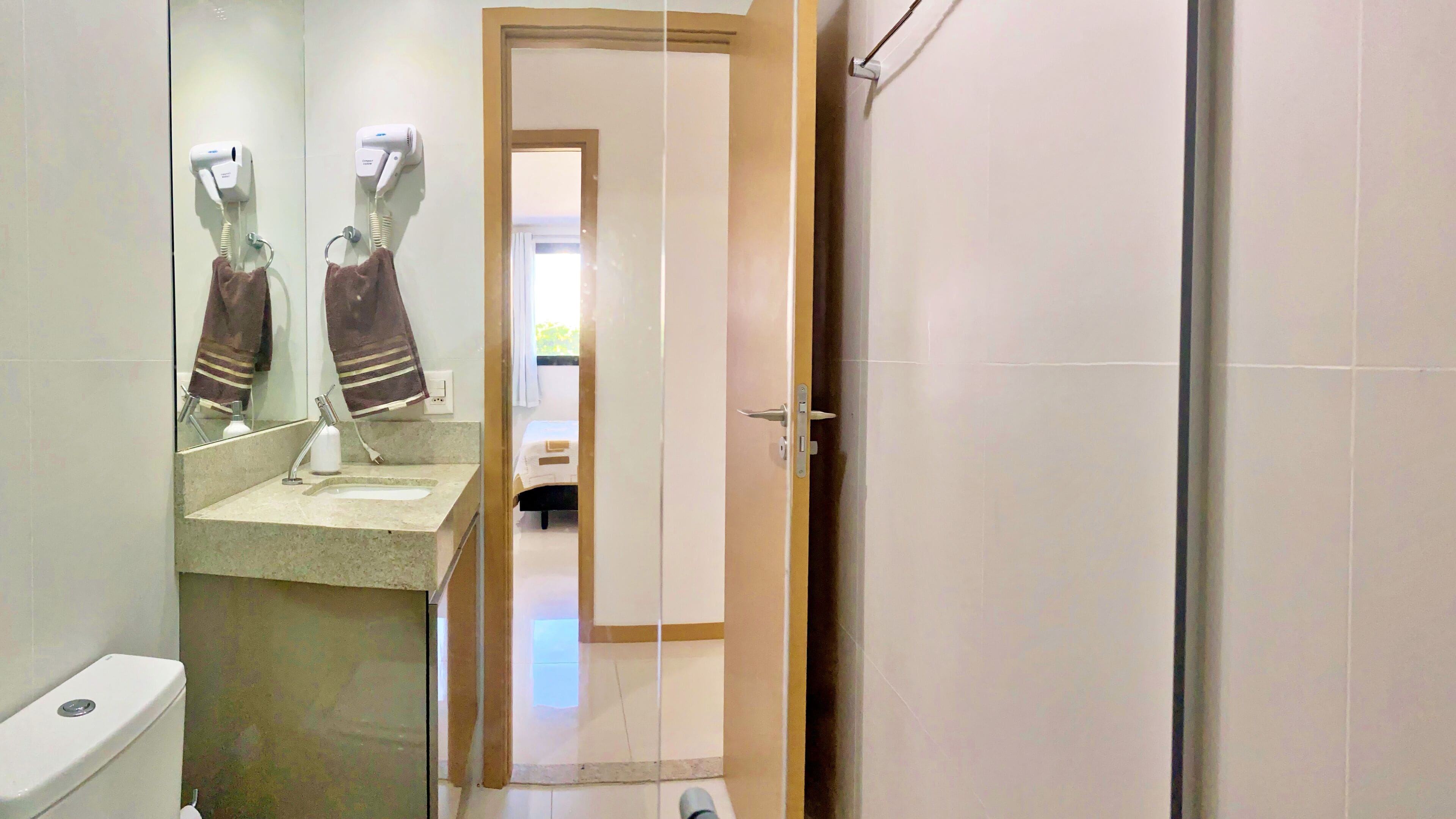 Ein Badezimmer mit Waschbecken, Spiegel, Handtuchhalter und Toilette.