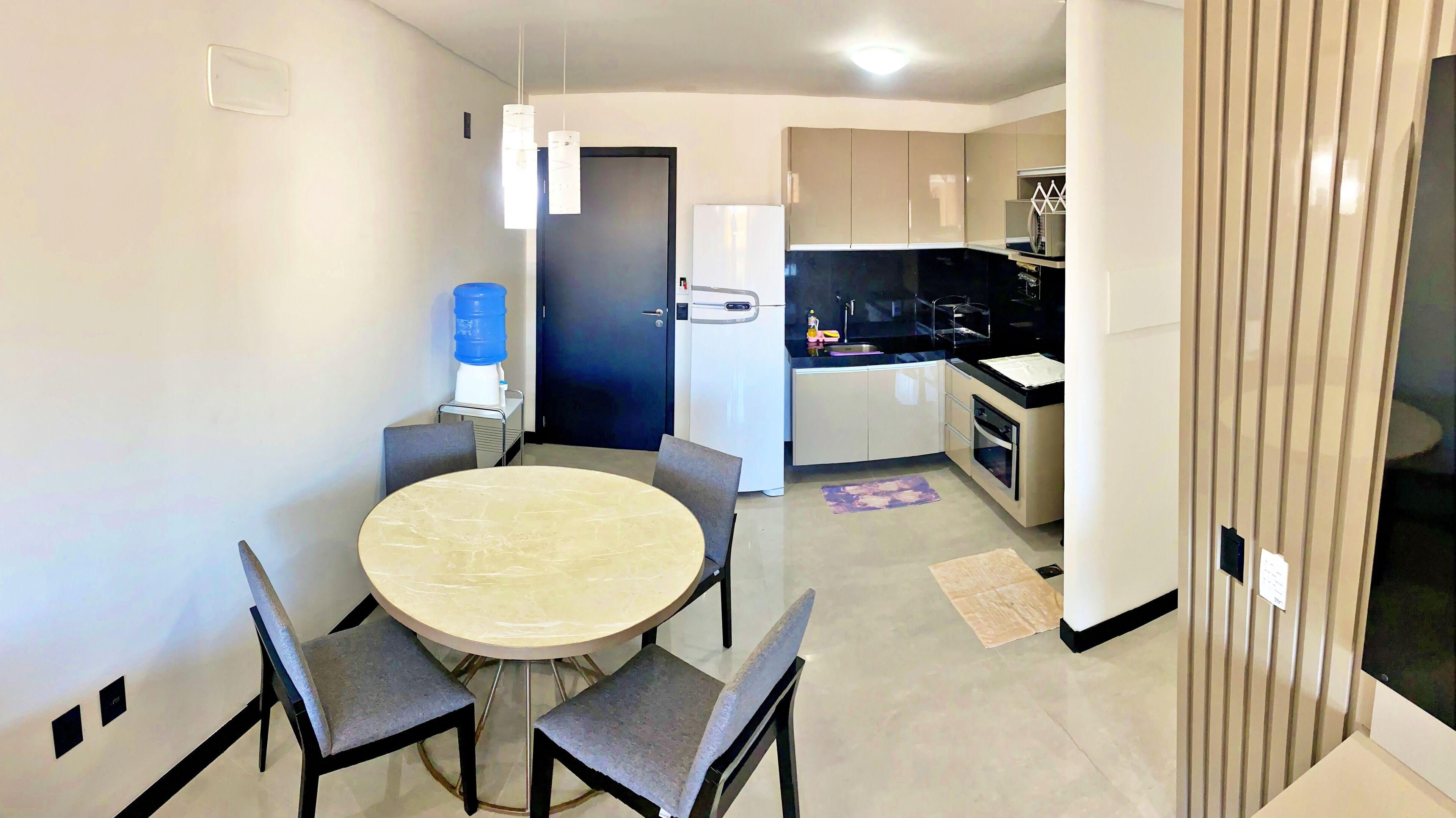 A compact kitchen with a refrigerator, stove, and sink. There is a dining area with a round table and four chairs.