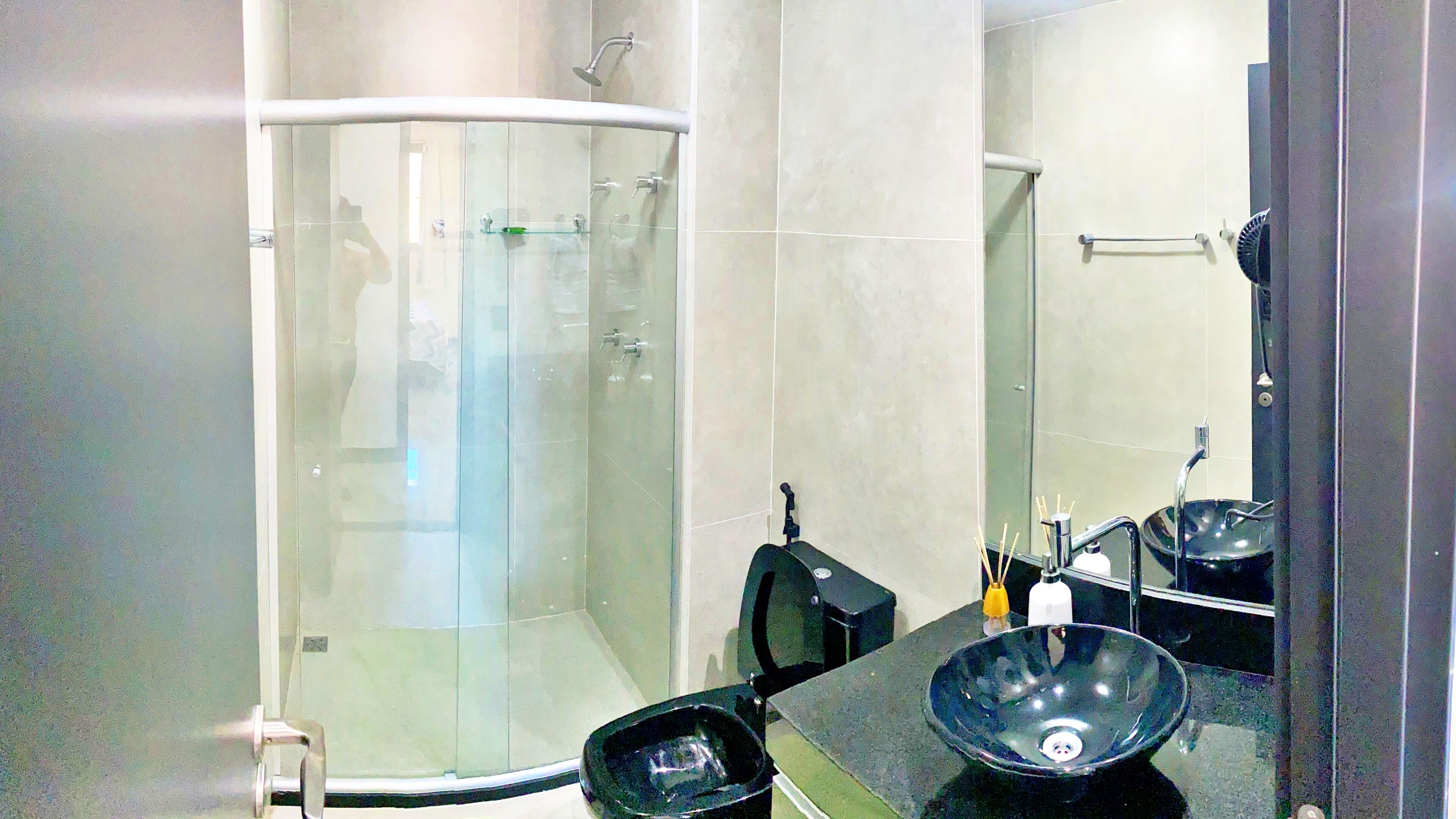 A modern bathroom with a glass-enclosed shower, a black sink, and a mirror.