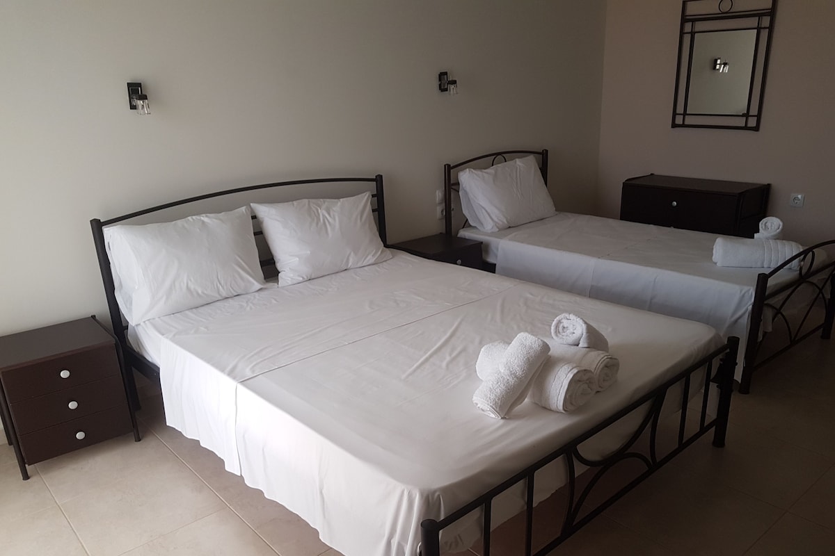A hotel room with two beds, a nightstand, a dresser, and a mirror on the wall.