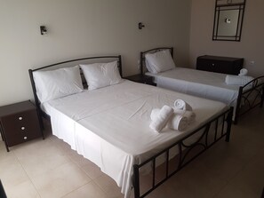 Habitación de hotel con dos camas, una mesita de noche, un aparador y un espejo en la pared.