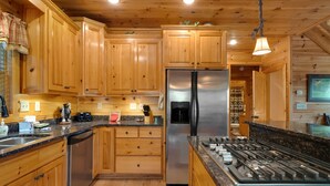 A kitchen with wooden cabinets, a stainless steel refrigerator, a gas stove, and a dishwasher.