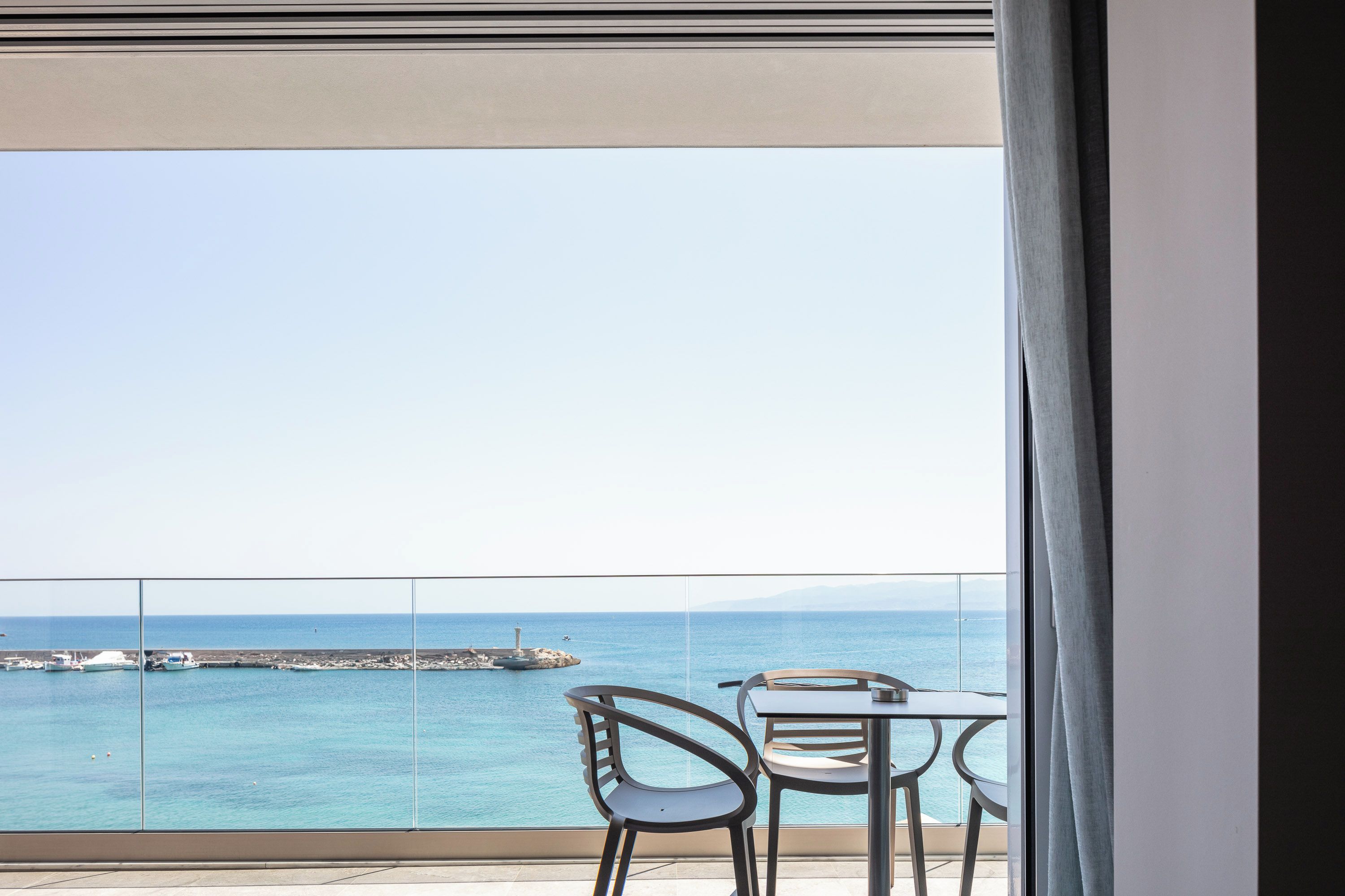 Un balcón con vistas al mar, que incluye dos sillas y una mesa.