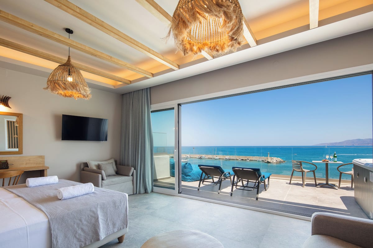 Una habitación de hotel moderna con un balcón grande, una cama, un escritorio y un televisor.