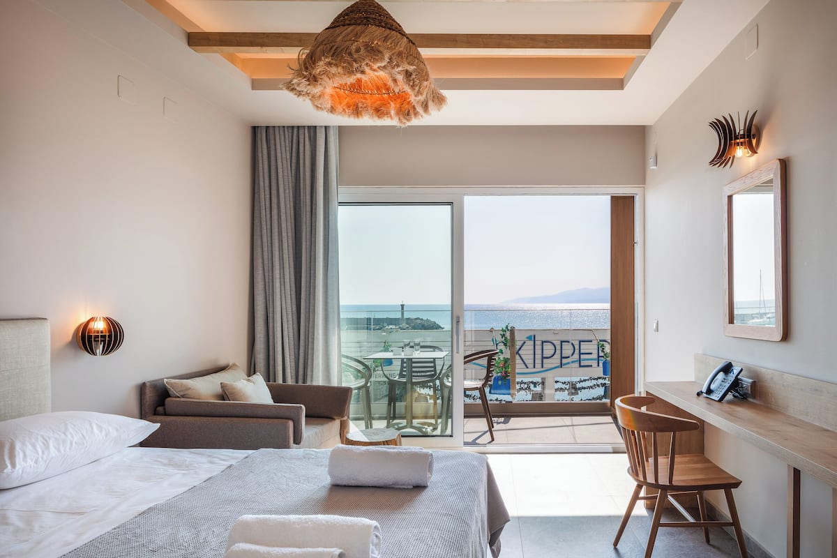 Habitación de hotel moderna con cama, escritorio y balcón con vistas al mar.